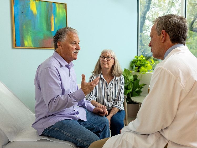 Older man speaking with his partner and a doctor during a medical appointment