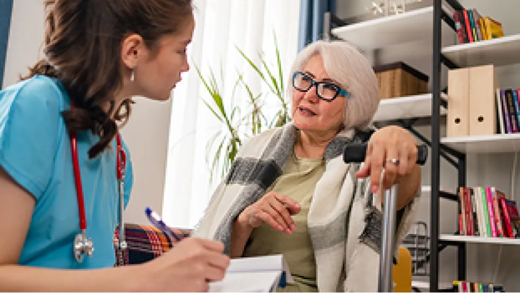 Nurse with stethoscope taking notes next to an older woman with a walking cane