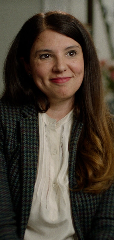 Audrey, actual patient with lung cancer, in a plaid blazer sitting in a living room, smiling