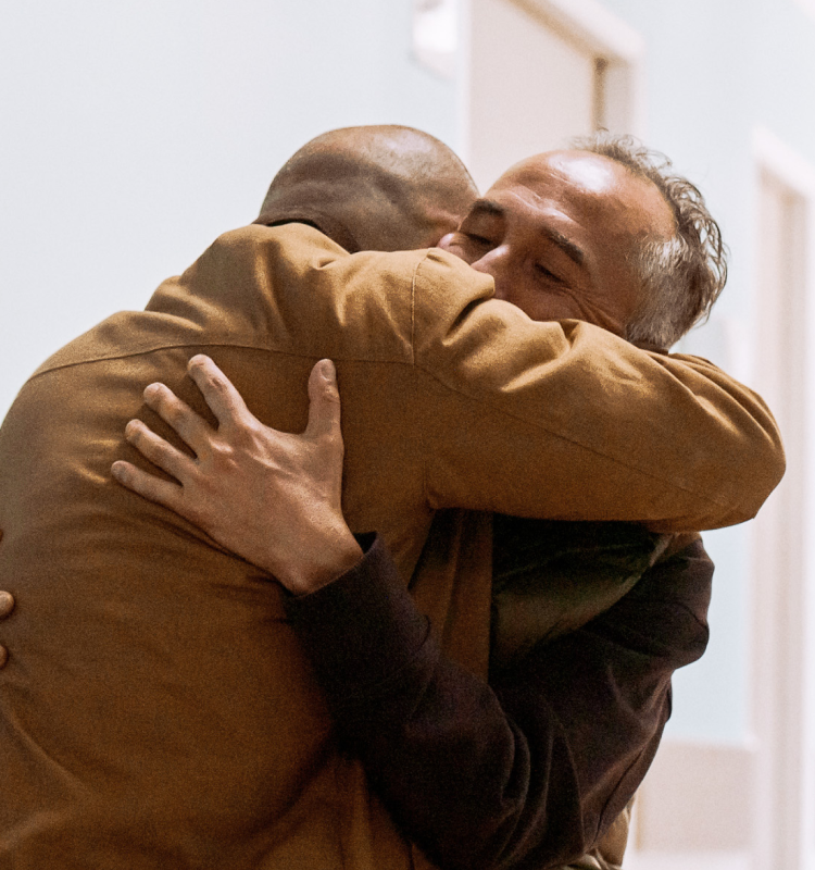 Patient and family member embracing in a hospital corridor as a clinician looks on