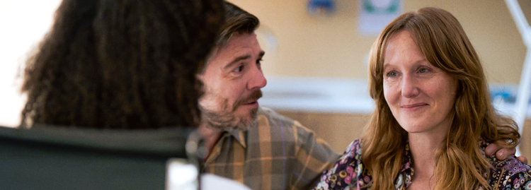 A smiling woman looks across at another person with a man next to her