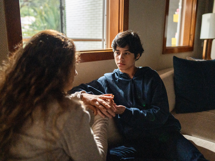Teenage boy holding hands with his caregiver during a conversation