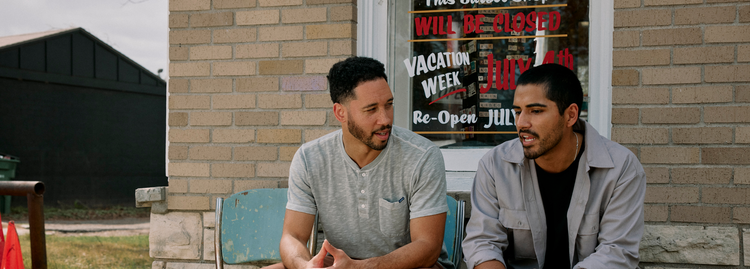 Two men sitting and talking outside a barber shop