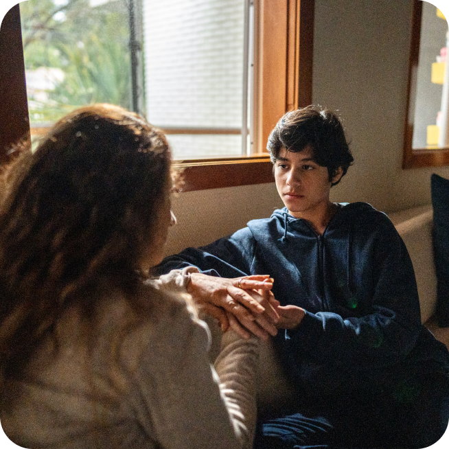 Teenage boy holding hands with his caregiver during a conversation
