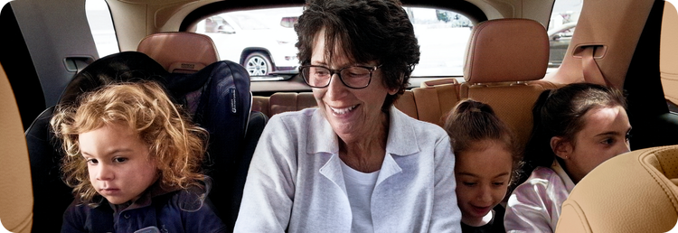 a woman sits in the back of a car with three small children