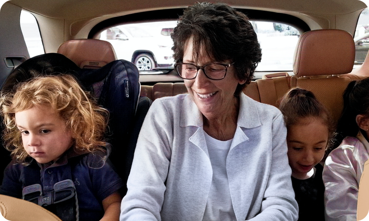 a woman sits in the back of a car with three small children