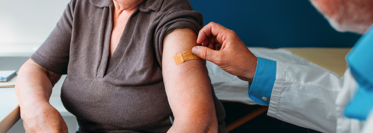 An older patient receiving a bandage on their arm