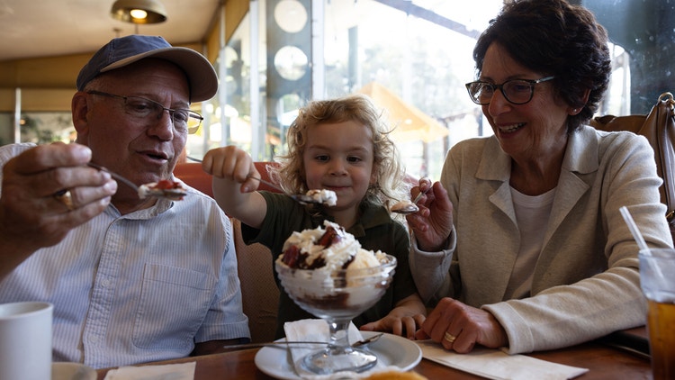 An older couple and a young child share an ice cream