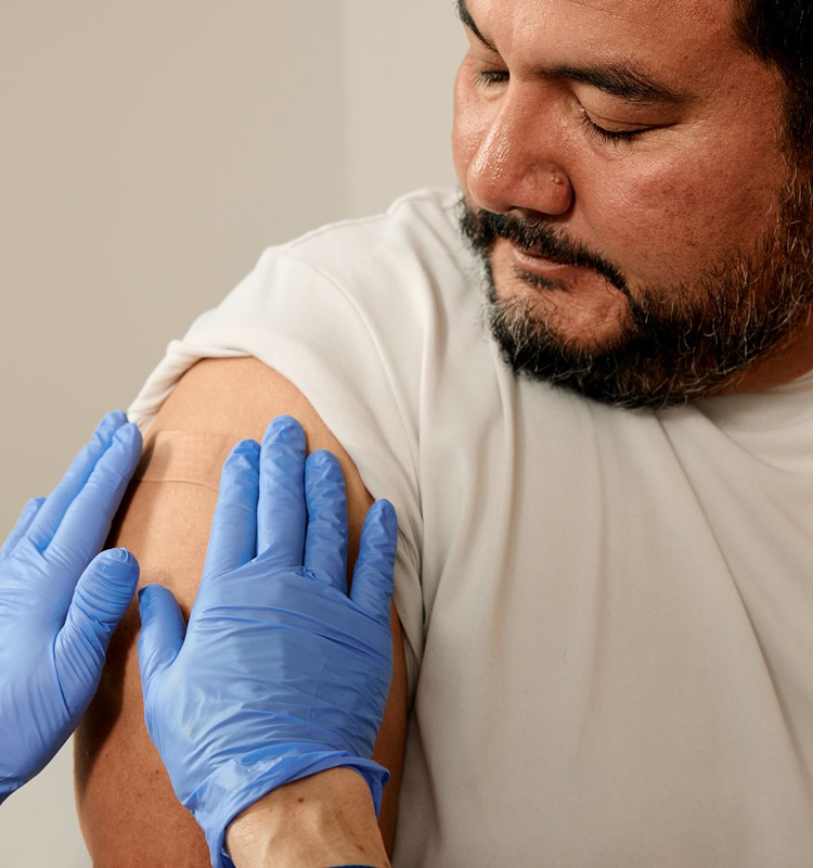 A man receiving a bandage from a healthcare professional on his arm