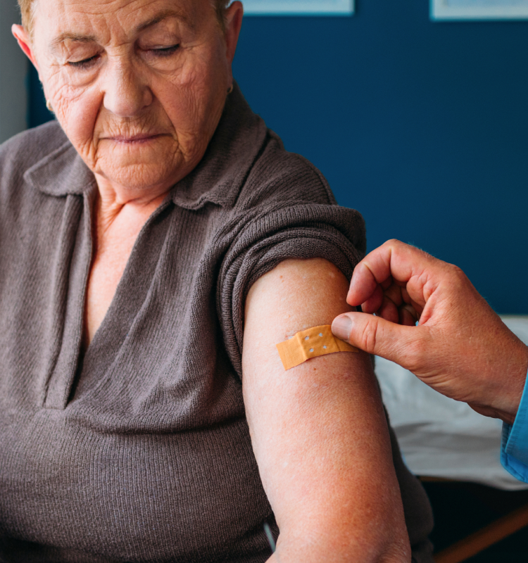 An older patient receiving a bandage on their arm
