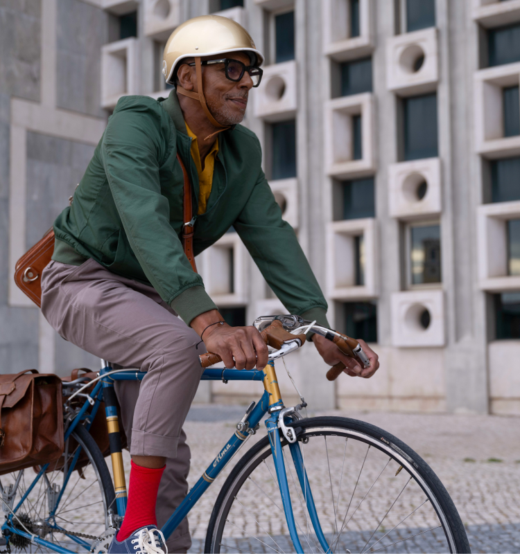 Older man in a gold helmet and green jacket riding a blue bicycle